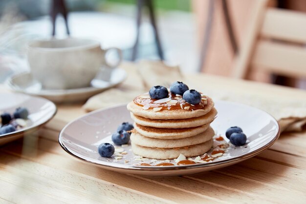 Crêpes végétaliennes traditionnelles avec des myrtilles fraîches et du sirop d'agave Tasse de café sur fond Petit-déjeuner à l'extérieur