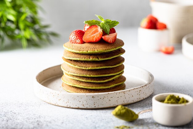 Crêpes vertes au thé matcha dans une assiette en céramique sur une surface blanche