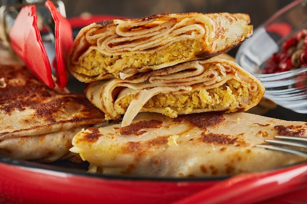 Photo crêpes à la viande et pinces sur fond de bois foncé.