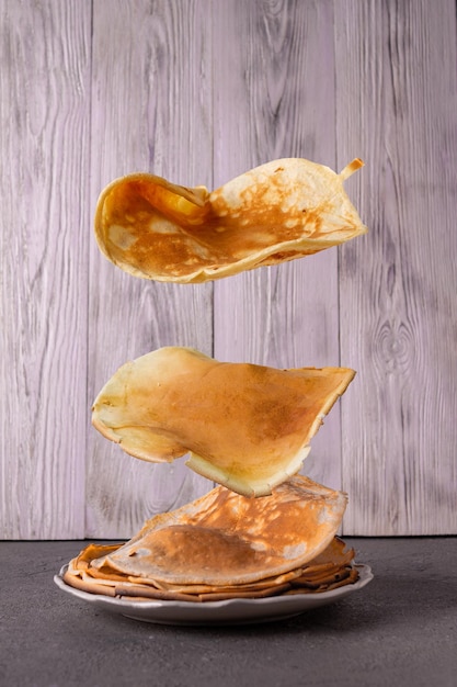 Crêpes volantes sur fond de planches de bois blanches