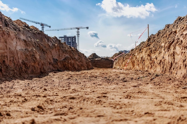 Creuser une tranchée Terrassement creuser une tranchée Longue tranchée en terre creusée pour poser un tuyau ou une fibre optique Construction de l'égout et du drainage Vue depuis la tranchée Sol argileux Une partie de l'image est floue