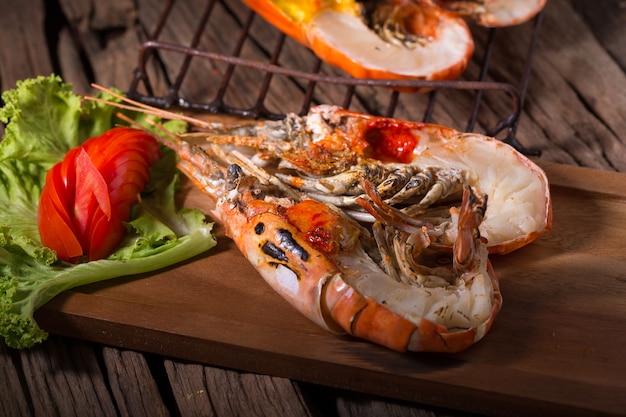 crevette géante grillée avec graisse crémeuse jaune sur la tête sur une plaque de bois