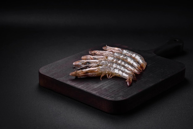 Crevette tigrée ou langoustine crue avec des épices et du sel sur une planche à découper en bois