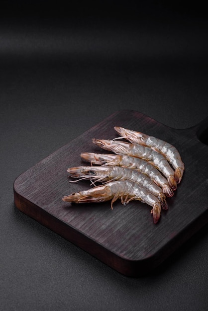 Crevette tigrée ou langoustine crue avec des épices et du sel sur une planche à découper en bois