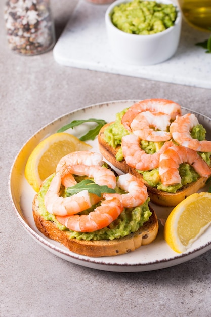 Des crevettes au pain grillé avec de l'avocat et du citron, des crevettes, un concept de petit déjeuner, des bruschettes.