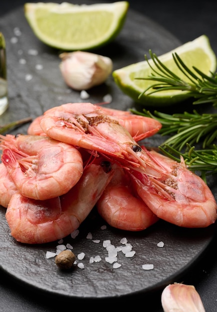 Crevettes bouillies sur une planche de tranches de citron épices sur fond noir