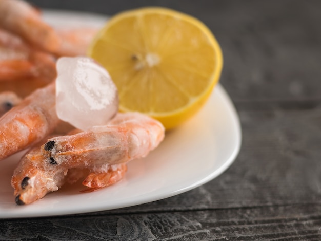 Crevettes Congelées Dans Un Bol Blanc En Terre Cuite Au Citron Sur Une Table En Bois Foncé.