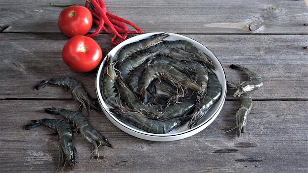 Crevettes ou crevettes crues fraîches dans une assiette ronde en céramique blanche avec un ingrédient sur la table. Vannamei.