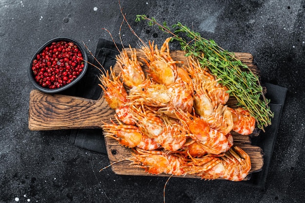 Crevettes de crevettes du Groenland cuites sur une planche de bois. Fond noir. Vue de dessus.