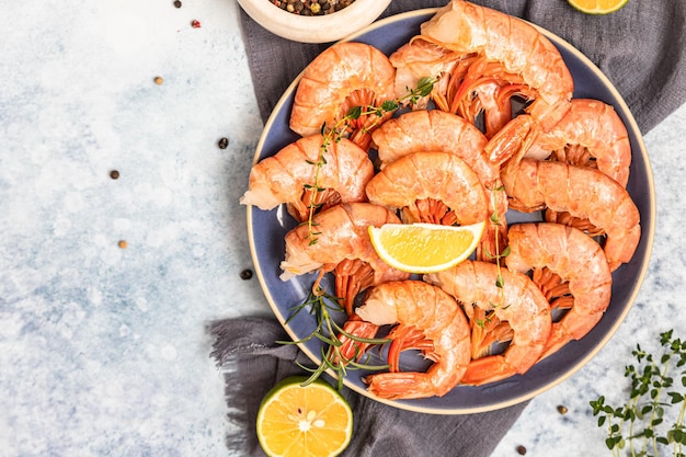 Crevettes ou crevettes fraîches avec du poivre de citron vert et des herbes sur fond de béton bleu