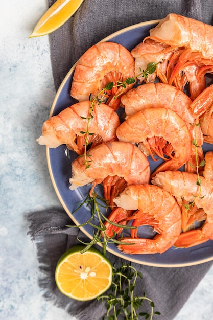 Crevettes ou crevettes fraîches avec du poivre de citron vert et des herbes sur fond de béton bleu