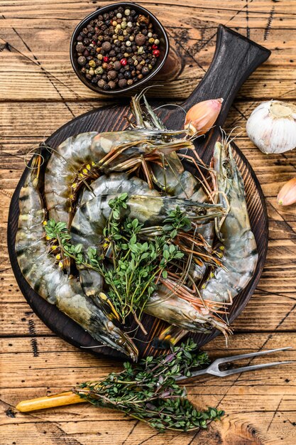 Crevettes crevettes tigrées noires crues sur une planche à découper avec des herbes