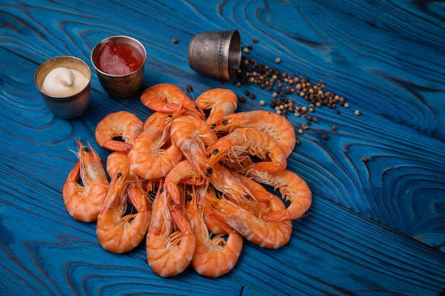 Crevettes cuites au poivre, sel et sauces sur une table en bois