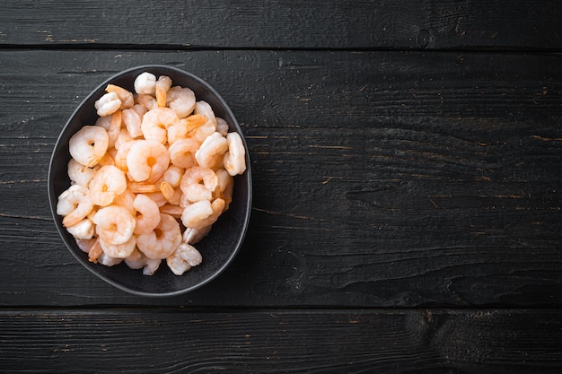 Crevettes décortiquées bouillies, sur table en bois noir, vue de dessus à plat