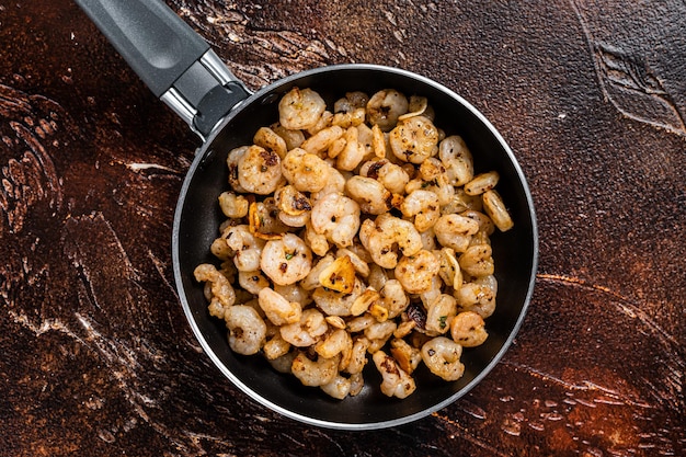 Crevettes décortiquées frites avec de l'huile d'olive à l'ail dans une poêle Vue de dessus sur fond sombre