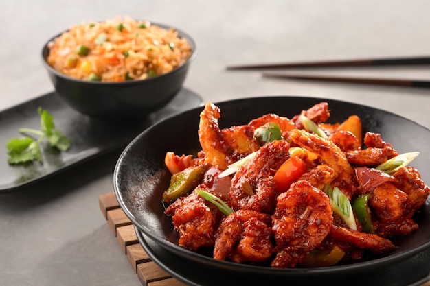les crevettes du Sichuan comprennent l'oignon de printemps, la tomate, le poivron, le riz frit schezwan et les baguettes servies dans un bol, vue de dessus de la cuisine chinoise
