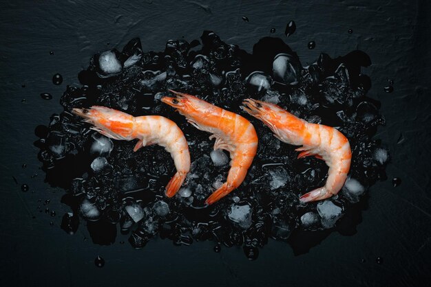 Crevettes de fond plat alimentaire et glace sur une vue de dessus de fond noir