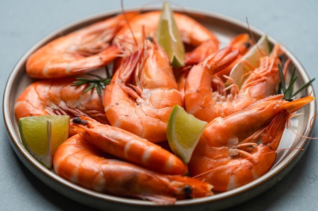 Photo des crevettes fraîches avec de la lime glacée et du romarin sur fond gris vue de haut