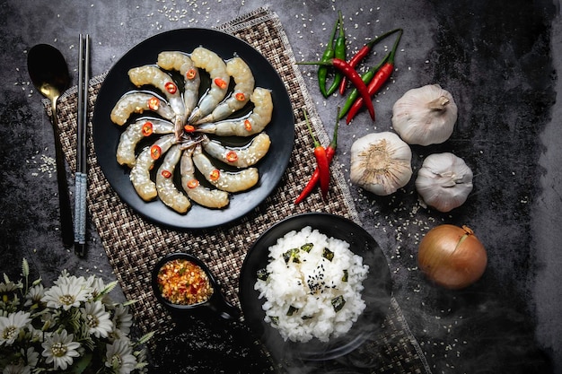 Crevettes fraîches trempées dans une sauce de poisson Assiette noire avec piment frais Fond sombre