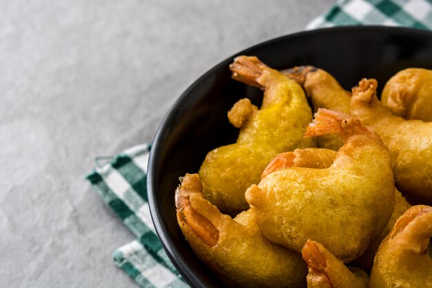 Crevettes frites dans un bol noir sur pierre grise