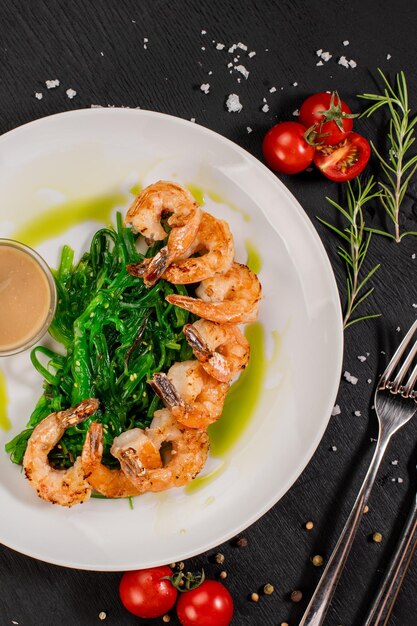 Crevettes frites savoureuses avec salade de chuka sur fond de bois