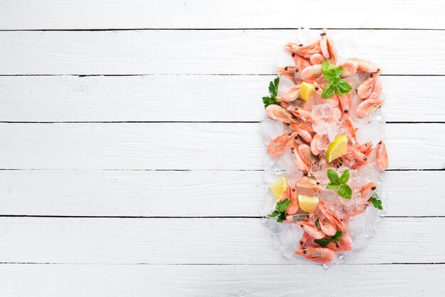 Crevettes avec glace et citron Fruits de mer Sur un fond en bois blanc Vue de dessus Espace de copie gratuit