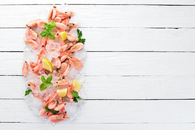 Crevettes avec glace et citron Fruits de mer Sur un fond en bois blanc Vue de dessus Espace de copie gratuit