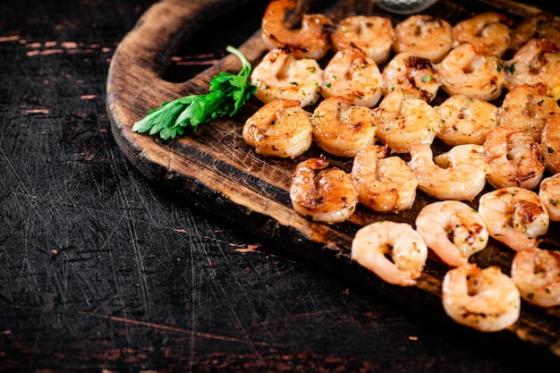 Crevettes grillées sur des brochettes avec du persil sur une planche à découper