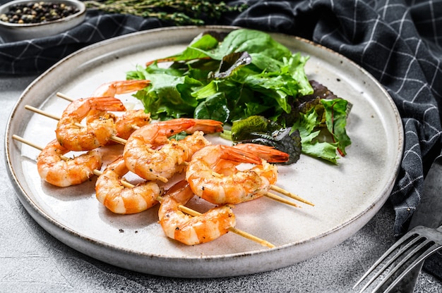 Crevettes grillées, crevettes en brochette avec salade d'épinards.