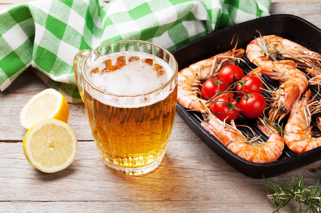 Crevettes grillées sur poêle et bière sur table en bois