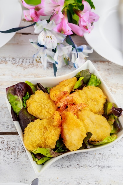 Crevettes panées frites avec salade et set de table.