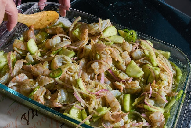 Crevettes préparées en aguachile avec des lanières d'oignons et des piments verts très épicés