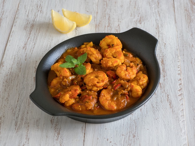 Crevettes à la sauce au curry dans un gros plan pan noir