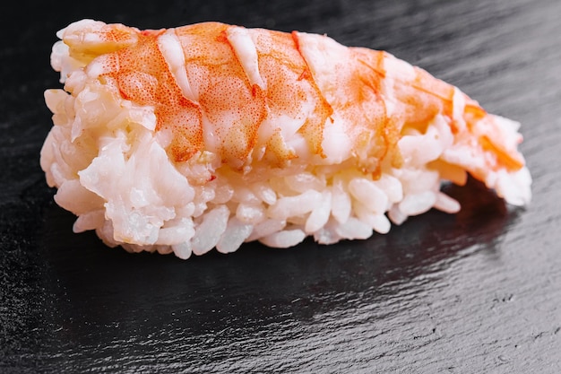 Crevettes de sushi et riz sur un bois noir