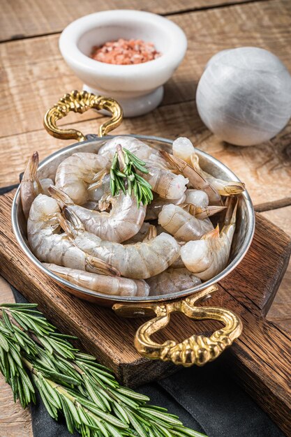 Crevettes tigrées blanches, gambas crues dans une poêle au romarin. Fond en bois. Vue de dessus.