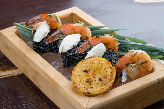 Crevettes tigrées avec riz noir et flans au fromage de Philadelphie servis sur du sel de l'Himalaya