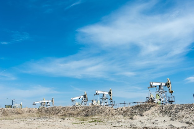 Cric de pompe à huile sur un champ pétrolifère. Fond de ciel bleu d'été. Extraction d'huile. Notion de pétrole.