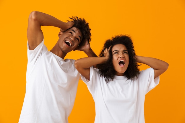 Crier émotionnel jeune couple africain mignon posant isolé sur un espace jaune.