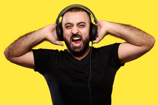 Crier homme arabe avec barbe écoute de la musique avec un casque jaune. Journée internationale du DJ