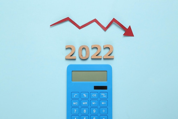 Crise économique 2022 Flèche tombant calculatrice et 2022 sur fond bleu