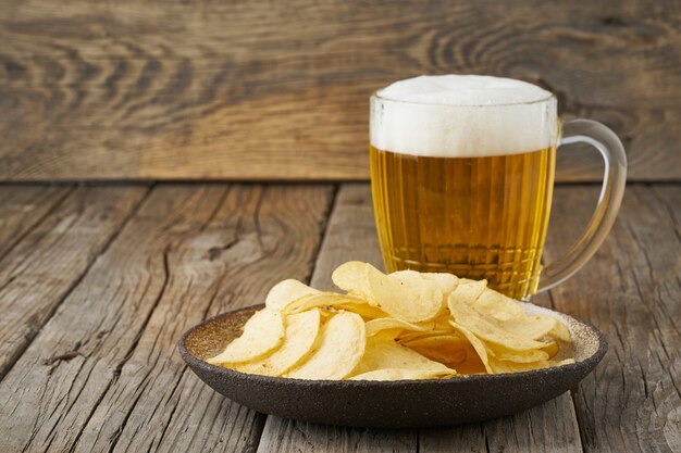 Crisp dans un bol avec de la bière dans un verre, vue de dessus, en bois, espace de copie