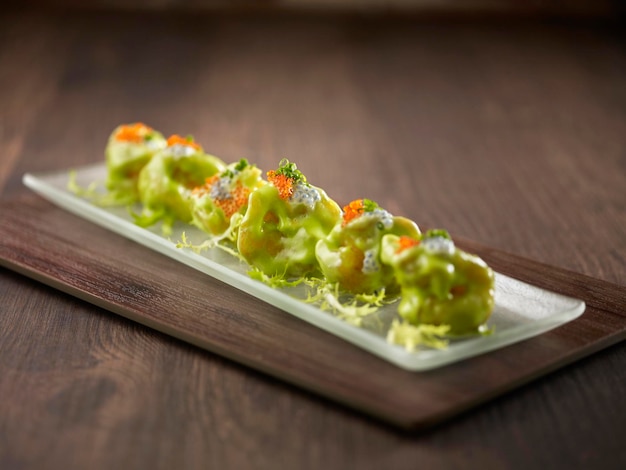 Crispyfried Crystal Prawns avec wasabi mayonnaise servi dans un plat isolé sur une planche à découper vue latérale sur fond sombre