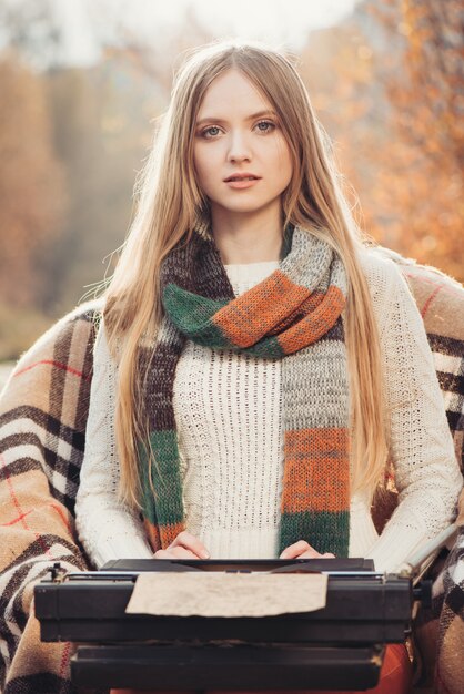 Écrivain femme travaille sur la vieille machine à écrire dans le parc en automne