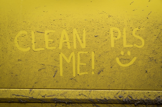 Écrivez le texte d'inscription des mots "nettoie-moi" sur la surface très sale de la voiture. Lavage de voiture concept.