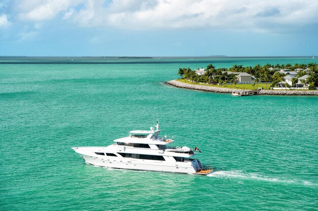 Croisière sur des bateaux touristiques ou un yacht flottant sur une île avec des maisons et des arbres verts sur une eau turquoise et un ciel bleu nuageux, du yachting et de la vie insulaire autour de la belle Key West en Floride, États-Unis