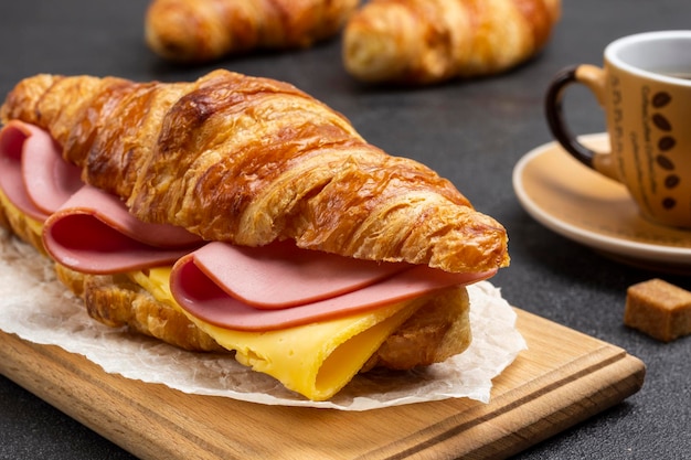 Croissant au jambon et fromage à bord. Fermer. Fond noir.