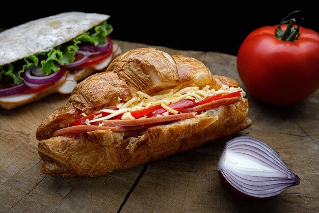 Croissant au jambon fromage et tomates sur une planche de bois