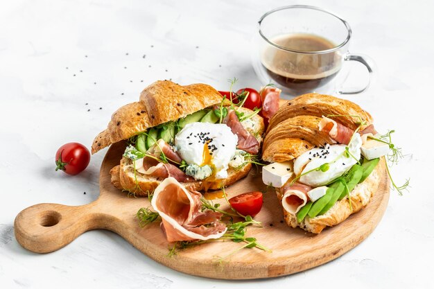 Croissant au prosciutto œuf poché jamon fromage bleu avocat microgin et tomates cerises apéritif méditerranéen concept de petit-déjeuner