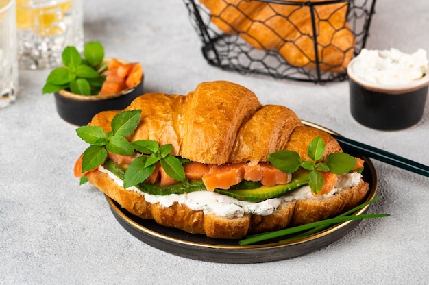 Croissant au saumon fumé salé, épinards et roquette servi sur plaque noire. Fermer. Petit-déjeuner français sain. Fruits de mer et fromage