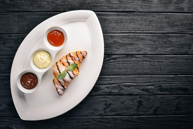 Croissant aux sauces sucrées Chocolat Vanille et Pêche Sur un fond en bois Vue de dessus